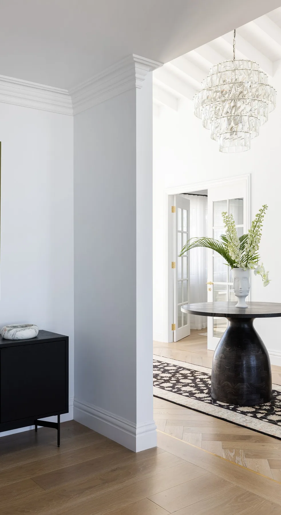 Elanora &mdash; hallway with chandelier, patterned runner and white panelled walls