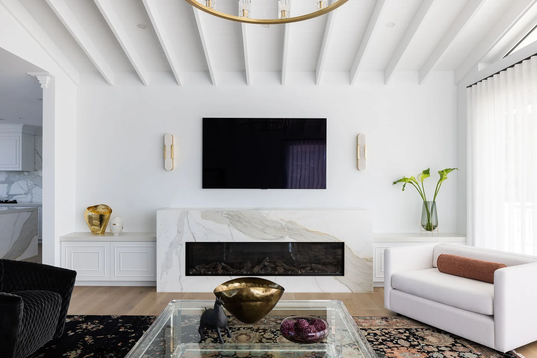 Elanora &mdash; marble fireplace with built-in TV, brass accents and glass coffee table
