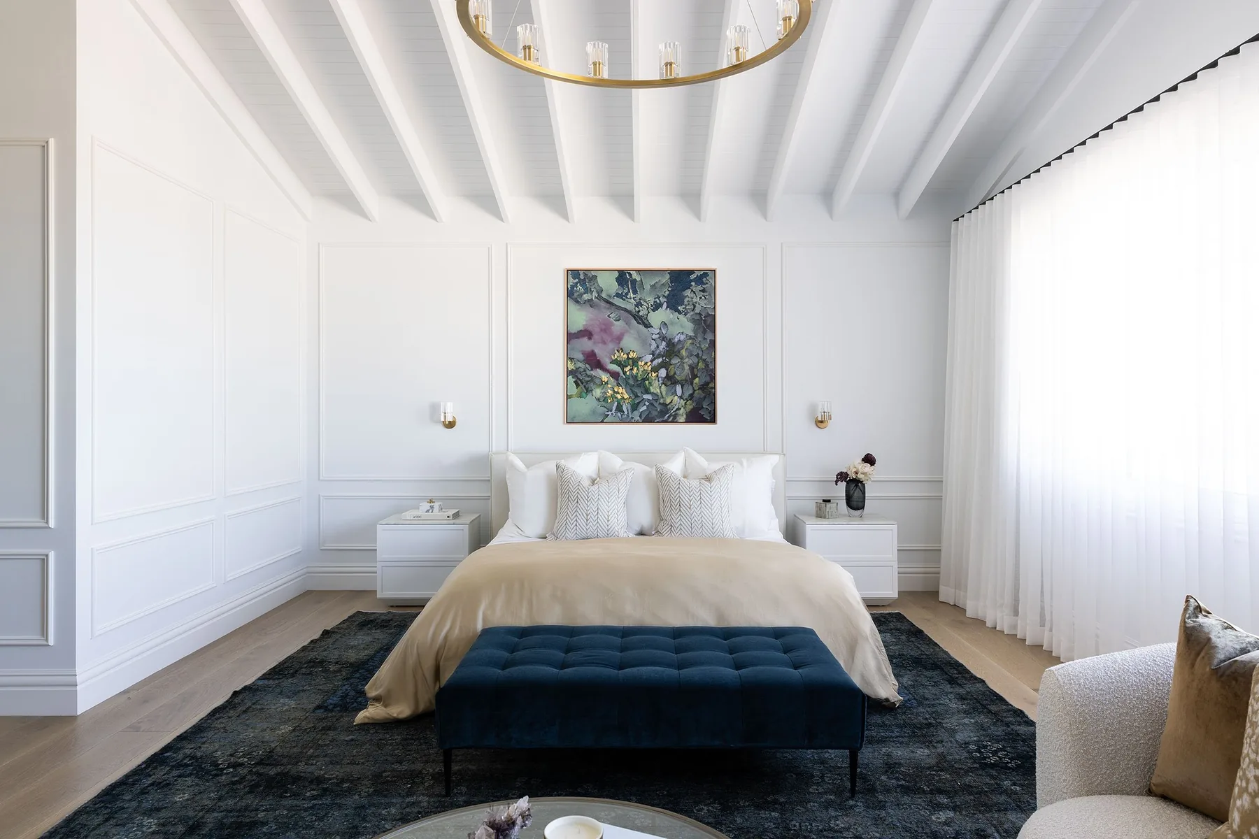 Elanora &mdash; main bedroom with navy tufted bench, vintage navy rug and white wainscoting