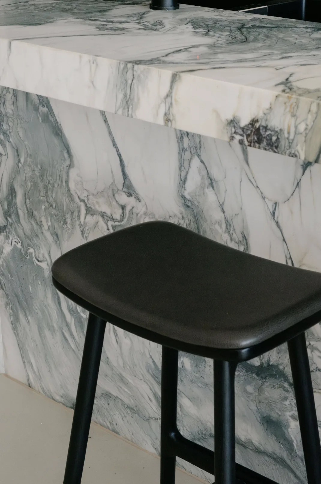 Freshwater &mdash; close detail of the marble island edge and a black leather stool