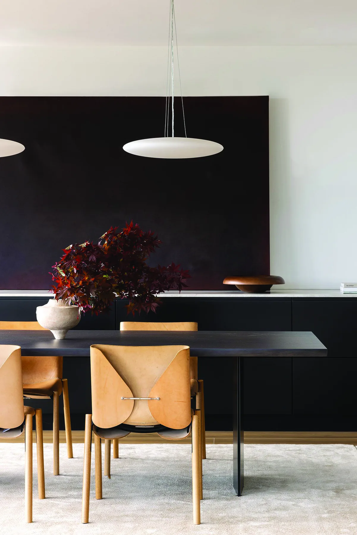Mosman 02 &mdash; dining area with black table, tan leather chairs and dark artwork
