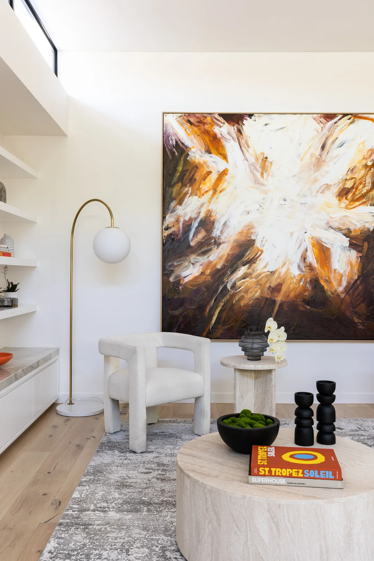 Russell Lea — arc floor lamp, bouclé chair and stone side table below an abstract painting
